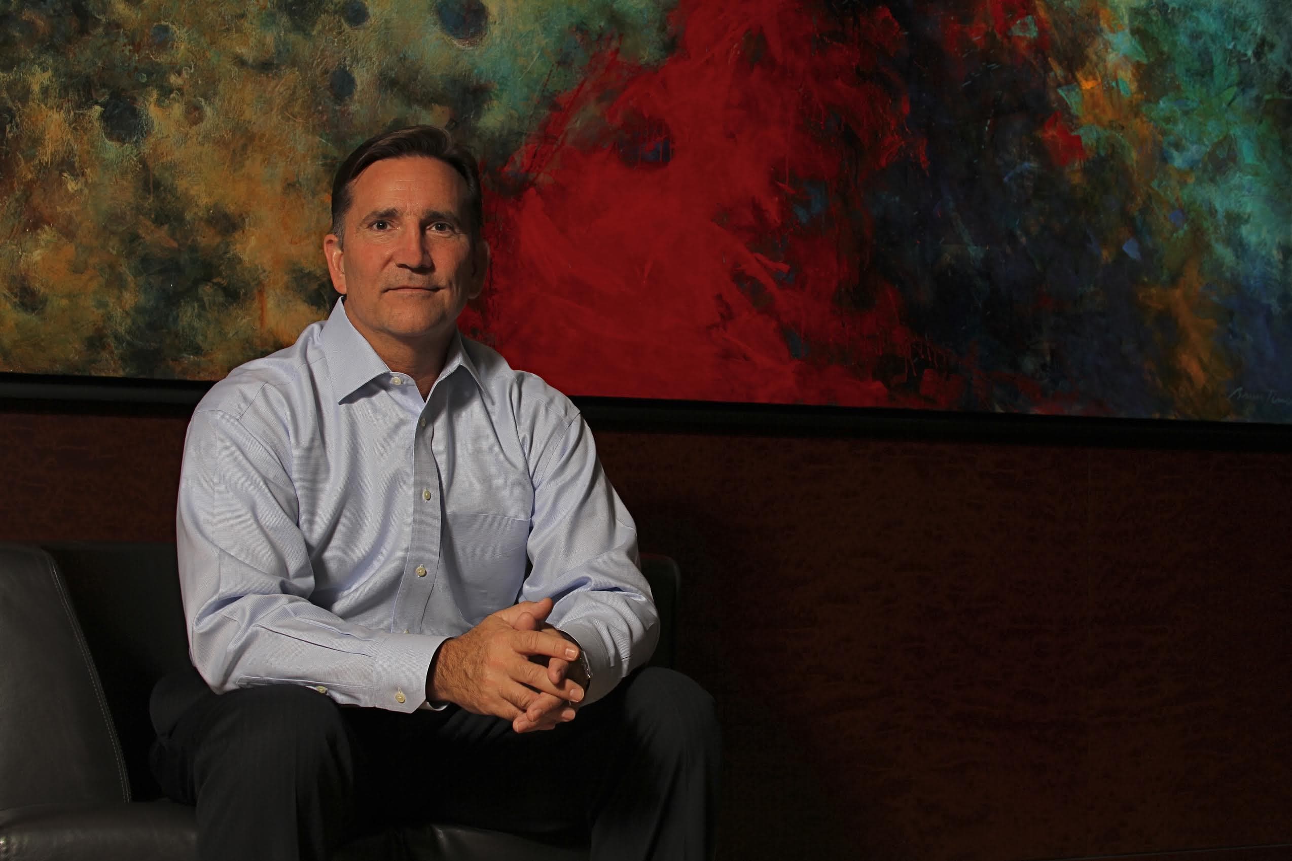Attorney Mark Williamson seated in his Dallas office before an expressive painting