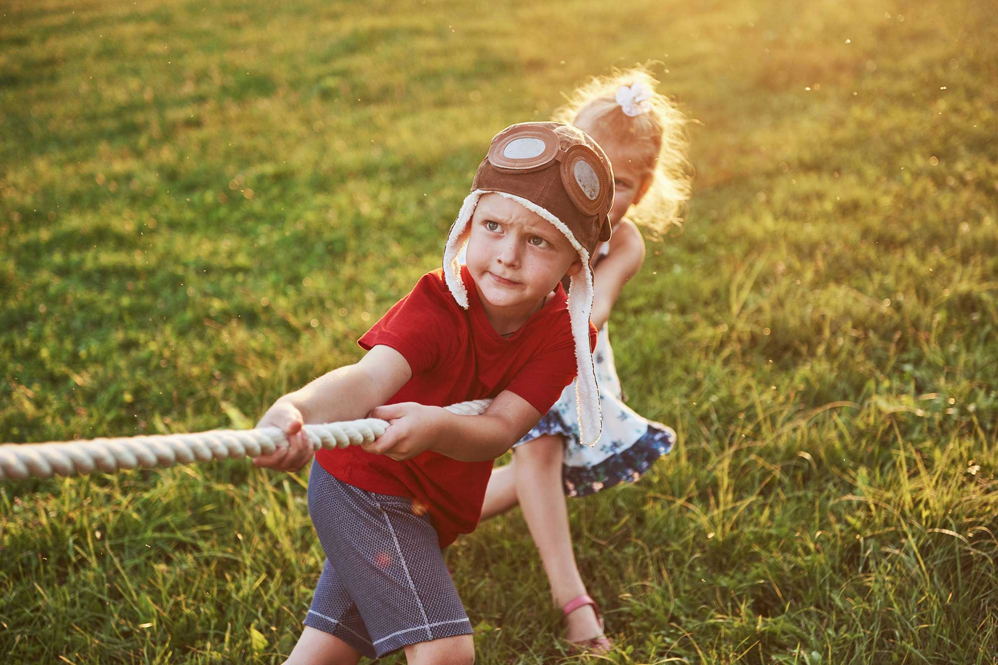 Two children pull a rope with an unseen force tugging at the other end.